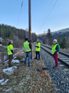 Fyra personer i gula reflexvästar står vid sidan av tågrälsen.